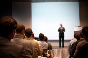 Business conference with lecturer and projection. Lecturer is blurred.